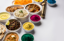 Happy Holy concept  showing Indian assorted lunch food like chicken, paneer butter masala, naan, jeera rice, black chana fry, jalebi, ras malai, thandai and Farsan with holi colours and pichkari